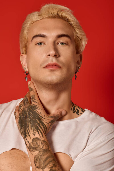 Attractive teenager poses confidently, displaying individuality with striking tattoos and fashion.