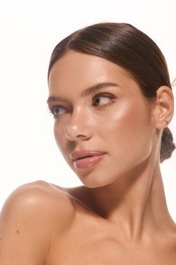 A beautiful young woman with natural makeup radiates freshness and simplicity in a bright setting.