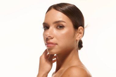 A young woman with natural makeup poses gracefully in front of a white backdrop.
