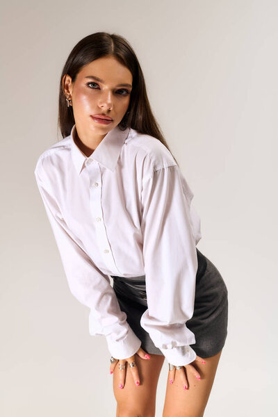 Beautiful young woman poses in a trendy autumn outfit featuring a white shirt and skirt.