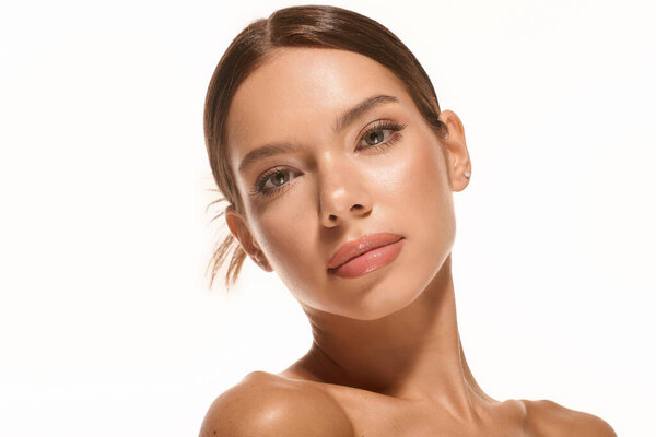 Captivating young woman showcases her natural beauty under bright lighting, exuding grace.