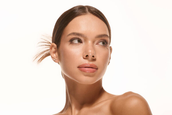 A young woman displays her natural makeup on a bright white background, showcasing her beauty.