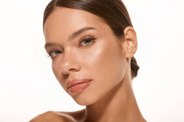 A young woman displays a fresh look with natural makeup set against a bright, white background.