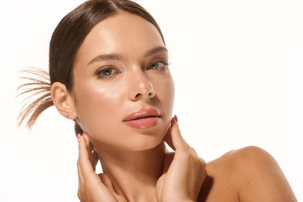 A beautiful young woman poses gracefully with natural makeup, highlighting her features softly.