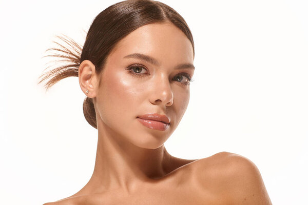 A beautiful young woman with natural makeup poses elegantly against a white background.