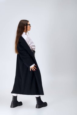 Elegant young woman poses confidently in a chic autumn outfit featuring a white shirt and skirt.