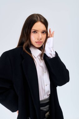 A beautiful young woman poses confidently in autumn attire, showcasing elegance and style.