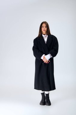 Young woman poses confidently in a trendy autumn outfit, highlighting her unique style.