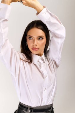 A young woman poses confidently in a stylish autumn outfit against a grey backdrop.