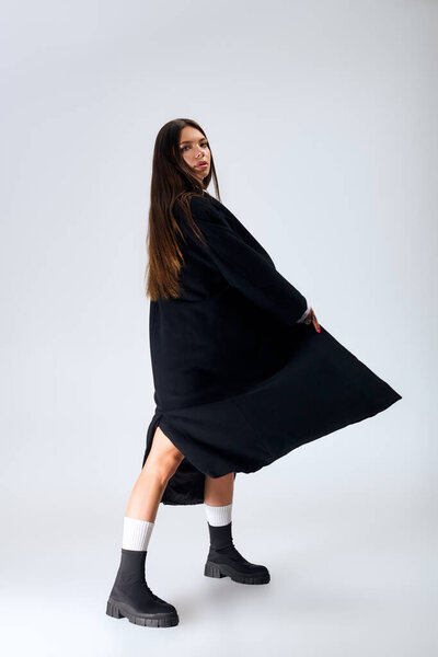 A beautiful young woman poses in a stylish autumn outfit, exuding confidence and grace.