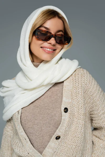 Femme gaie en foulard et lunettes de soleil élégantes souriant isolé sur gris — Photo de stock