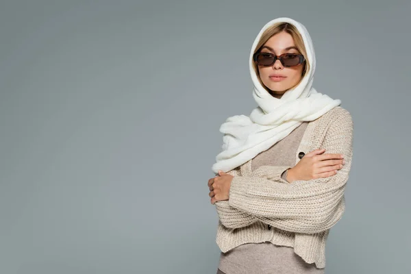 Donna bionda in velo e occhiali da sole alla moda in posa con le braccia incrociate isolate sul grigio — Foto stock