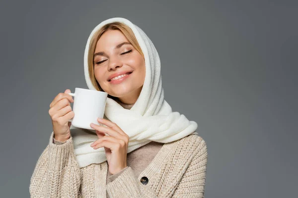 Femme heureuse en foulard d'hiver et cardigan tricoté tenant tasse de café isolé sur gris — Photo de stock