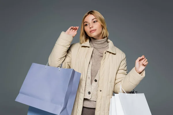 Blonde Frau im beigen Winteroutfit mit Einkaufstaschen in grau — Stockfoto