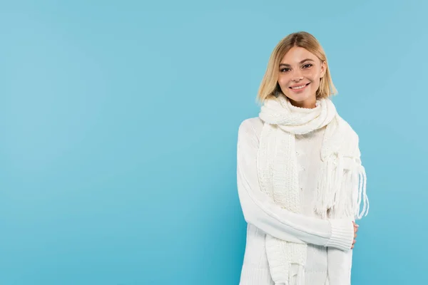 Pretty woman in warm scarf and sweater looking at camera isolated on blue — Stock Photo