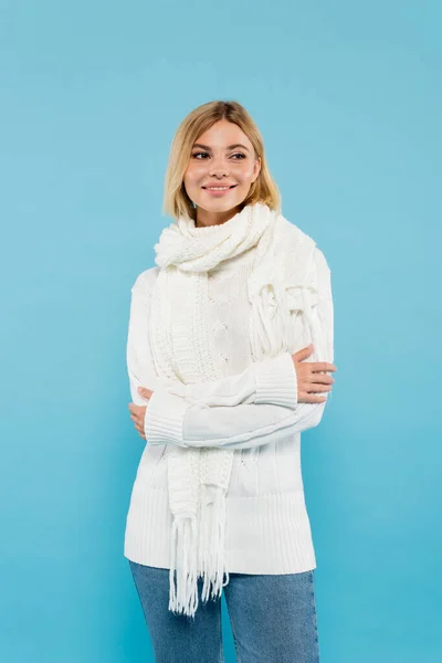 Smiling woman in warm sweater and scarf looking away isolated on blue — Stock Photo