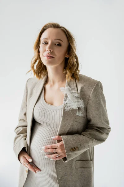 Porträt einer jungen Schwangeren in Jacke, die isoliert auf grau in die Kamera blickt — Stockfoto