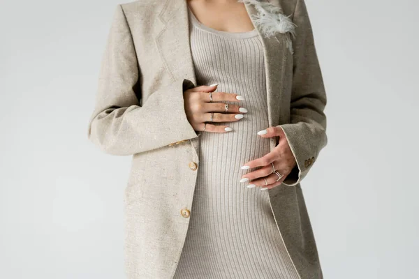 Vista cortada de mulher grávida elegante em casaco tocando barriga isolada em cinza — Fotografia de Stock
