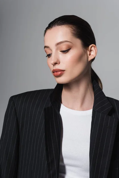Trendy giovane donna in giacca nera guardando giù isolato sul grigio — Foto stock