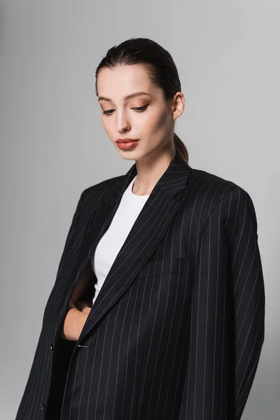Elegante donna con trucco posa in giacca nera isolata su grigio — Foto stock