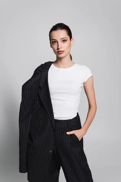 Stylish woman in t-shirt and striped suit posing on grey background — Stock Photo