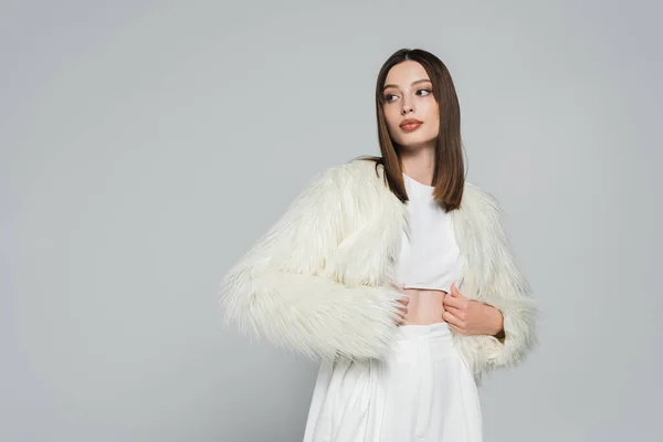 Jovem mulher em roupa totalmente branca e casaco de pele falso na moda posando isolado no cinza — Fotografia de Stock