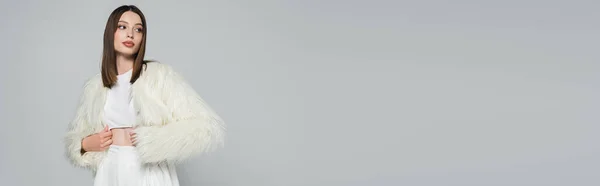 Jeune femme en tenue totalement blanche et veste en fausse fourrure tendance posant isolée sur gris, bannière — Photo de stock