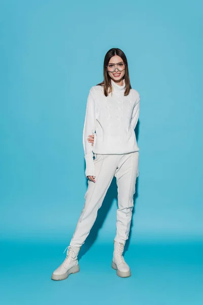 Full length of happy and stylish woman in totally white outfit posing on blue — Stock Photo