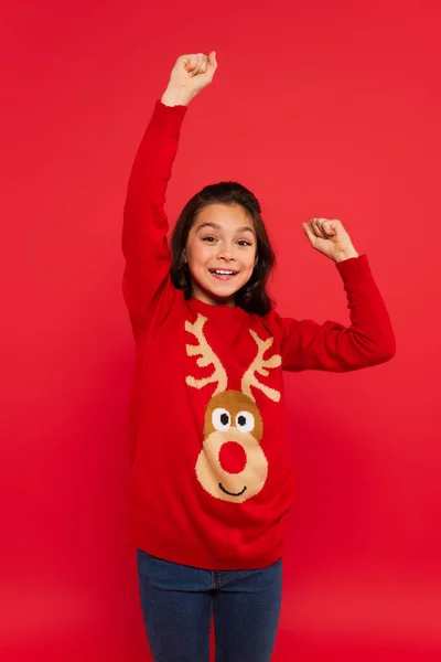 Criança excitada em camisola de inverno gesticulando e alegrando-se isolado no vermelho — Fotografia de Stock