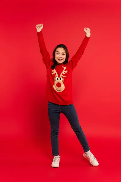 Full length of amazed child in sweater and jeans gesturing on red — Stock Photo