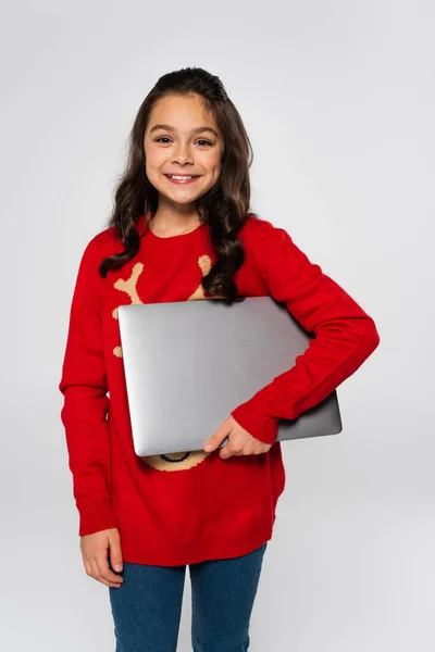 Enfant heureux en pull de Noël rouge tenant ordinateur portable isolé sur gris — Photo de stock