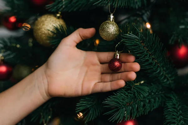Cropped view of kid touching shiny ball on Christmas tree — Stock Photo