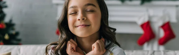 Pleased preteen child closing eyes during Christmas celebration at home, banner — Stock Photo