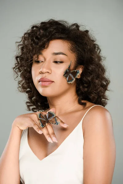 Joven mujer afroamericana con mariposas en la mano y la cara aislada en gris — Stock Photo