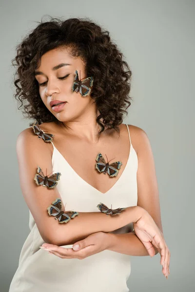 Кудрявая африканская американка с бабочками на теле и щекой, изолированной от серого — Stock Photo