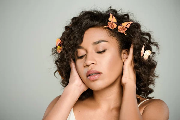 Junge afrikanisch-amerikanische Frau mit Schmetterlingen im Haar posiert isoliert auf grau — Stockfoto
