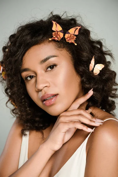 Sensual african american woman with butterflies in hair looking at camera isolated on grey — Stock Photo