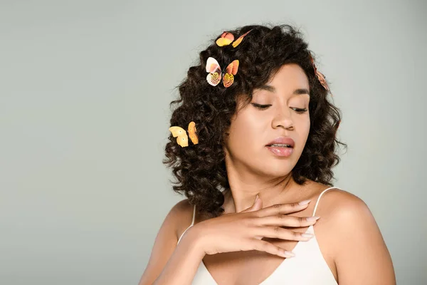 Sinnliche afrikanisch-amerikanische Frau mit Schmetterlingen im Haar, die Schulter isoliert auf grau betrachtet — Stockfoto