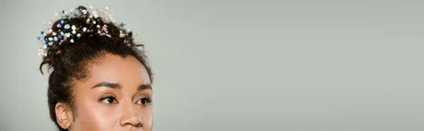 Обрізаний вид на молоду афроамериканку з квітами гіпсофіли в волоссі ізольовані на сірому, банер — стокове фото