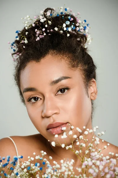 Молода афроамериканка з квітами у волоссі тримає букет з гіпсофіли ізольовані на сірому — стокове фото