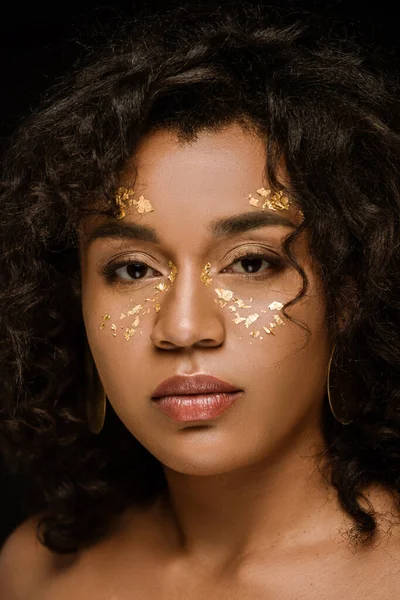 Brunette african american woman with golden body paint on cheeks isolated on black — Stock Photo