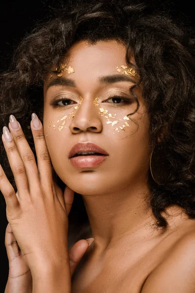 Brunette afro-américaine avec de la peinture dorée sur les joues isolées sur noir — Photo de stock