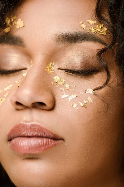 Крупным планом брюнетки африканской американки с золотой краской на щеках и закрытыми глазами — стоковое фото