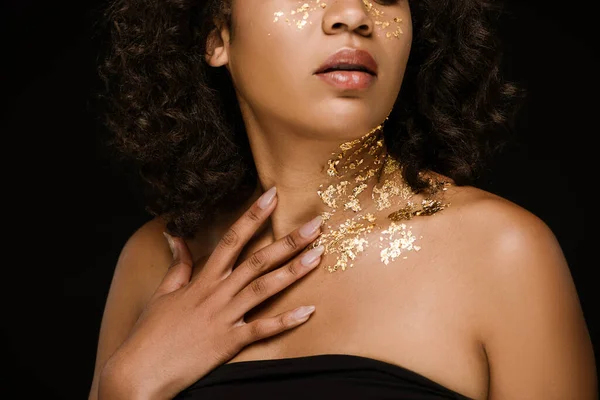 Обрезанный вид молодой африканской американки с золотой краской на лице и шее изолированы на черном — стоковое фото