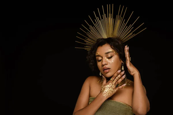 Pretty african american woman with golden accessories and paint on face posing isolated on black — Stock Photo