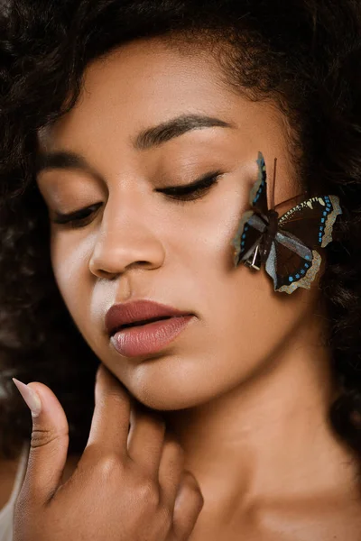 Close up of curly african american woman with butterfly on face — Stock Photo