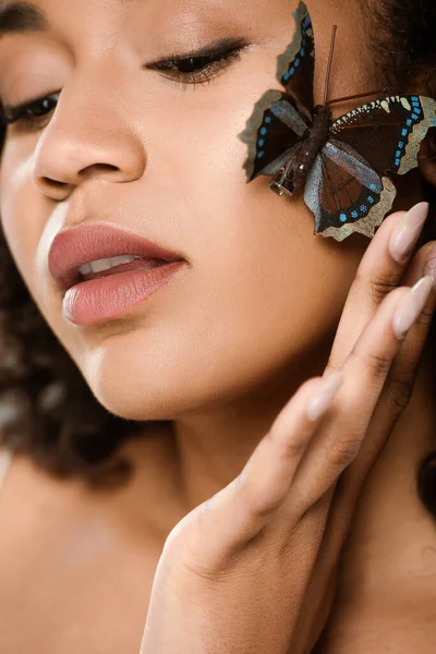 Primer plano de sensual y joven mujer afroamericana con mariposa en la mejilla - foto de stock