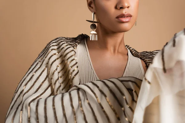 Vista recortada de rica mujer afroamericana en joyas de oro posando con chal aislado en beige - foto de stock