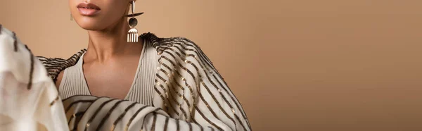 Обрізаний вид на багату афроамериканську жінку в золотих прикрасах позує ізольовано на бежевому, банер — стокове фото