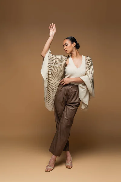 Afrikanische Amerikanerin in Goldschmuck und Schal posiert in voller Länge auf beige — Stockfoto